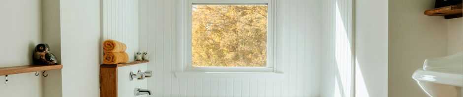 A built-in bathtub under a window in a small bathroom